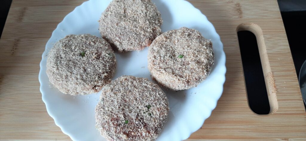 4 veg cutlet patties deeped with breadcrumbs in a plate