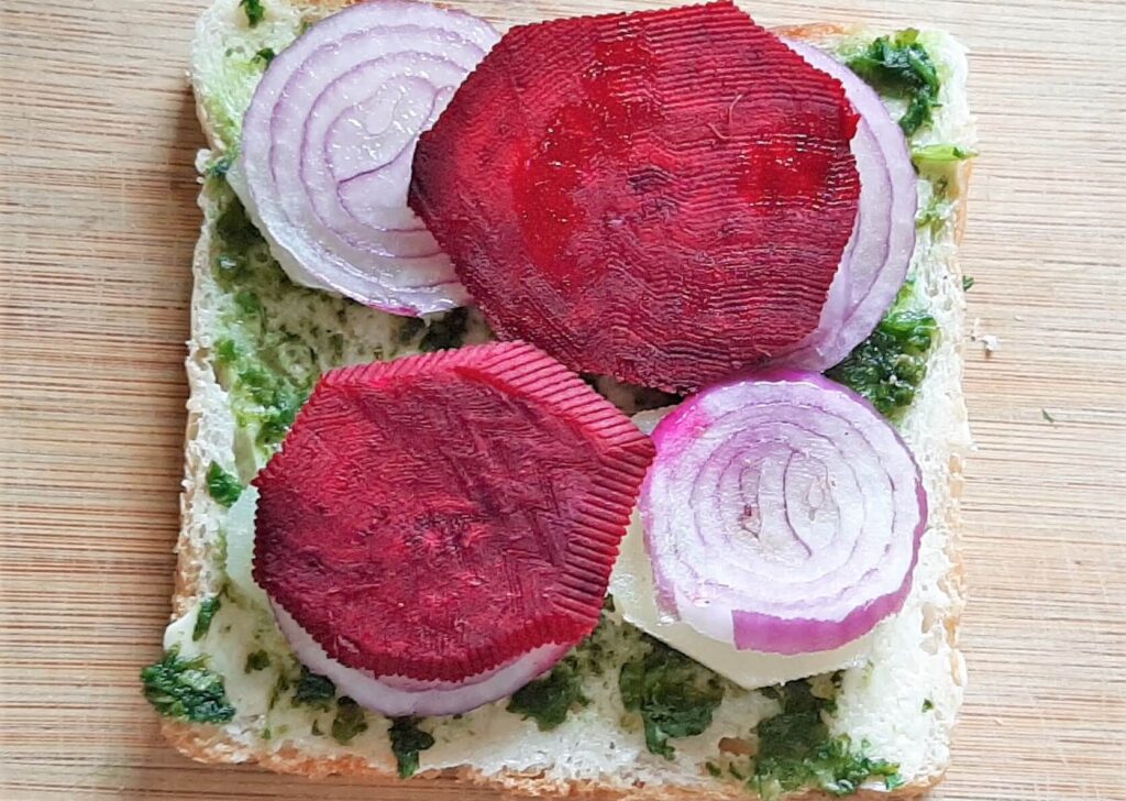 Adding beetroot slices on vegetarian sandwich